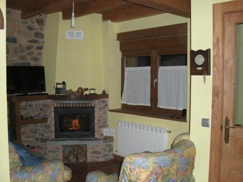 a living room with a fireplace and two chairs at Casa Aires de Pajares in Camplongo