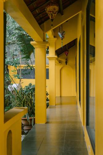 a hallway of a building with yellow columns and plants at Tam Coc Mango Homestay - Free Swimming Pool in Ninh Binh