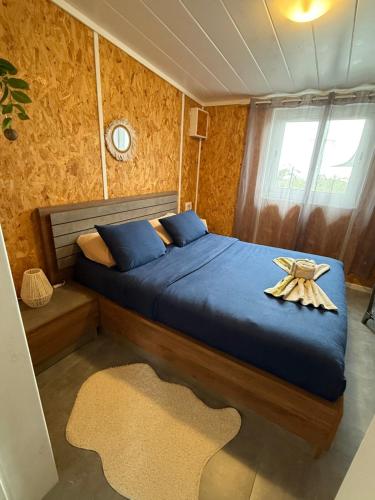 a bedroom with a blue bed with a towel on it at Lebon Coin Tranquille in Le Tampon