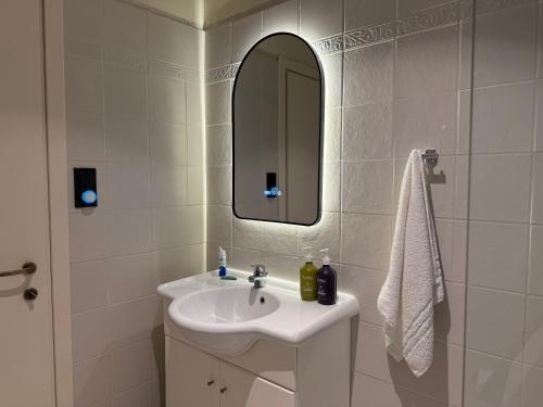a white bathroom with a sink and a mirror at Villa Rhodos Skiathos in Skiathos