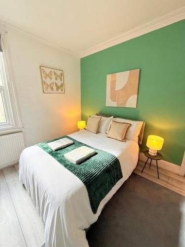 a bedroom with a large bed with a green wall at Large 3 bed 2 bath modern apartment in Finchley