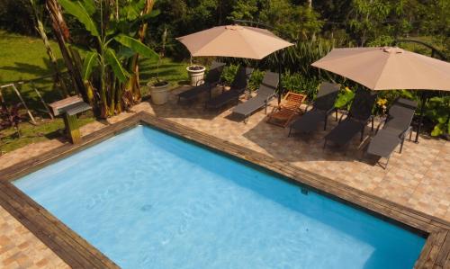 a swimming pool with umbrellas and chairs and a pool at Sitio Chacara Piscina Aquecida Acesso Asfaltado in Juquitiba