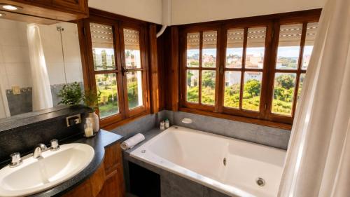 a bathroom with a tub and a sink and windows at Mojomar Pinamar Hotel in Pinamar