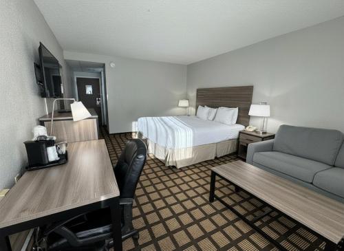 a hotel room with a bed and a couch at Baymont by Wyndham Queensbury/Lake George in Queensbury