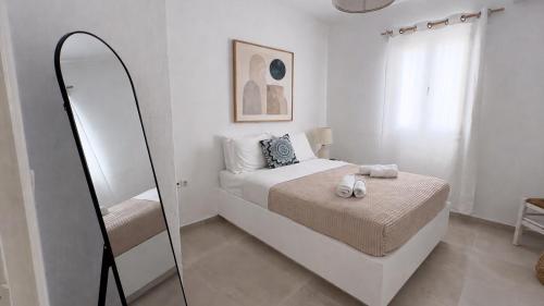 a white bedroom with a bed and a mirror at Aloni Ios in Mylopotas