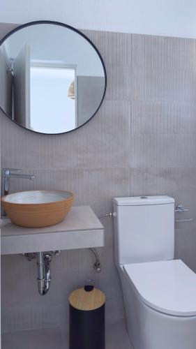 a bathroom with a sink and a mirror and a toilet at Aloni Ios in Mylopotas
