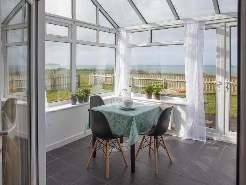 a dining room with a table and chairs and windows at Hayloft - Ukc4678 in Clynnog-fawr