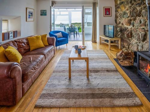 a living room with a brown leather couch and a fireplace at Hayloft - Ukc4678 in Clynnog-fawr