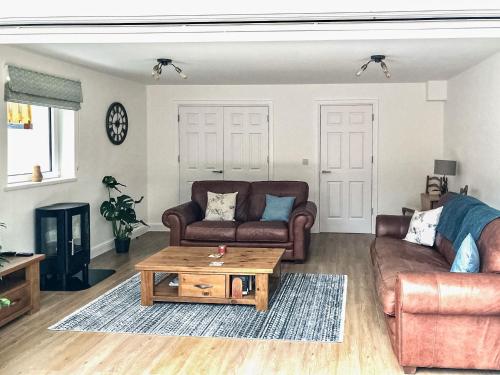 a living room with two couches and a coffee table at Clock Tower Cottage in Whitchurch
