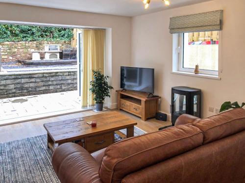 a living room with a couch and a television at Clock Tower Cottage in Whitchurch