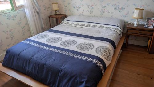 a bed with a blue and white comforter on it at Marychris in Saint-Loubès