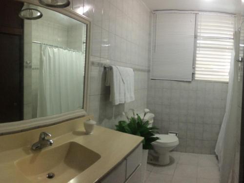 y baño con lavabo, aseo y espejo. en Isla Verde Aptm, en San Juan