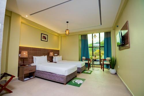 ein Schlafzimmer mit Bett, Schreibtisch und Fernseher in der Unterkunft Green Mountain Hotel in Arusha
