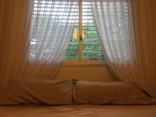 a bedroom with a bed and a window with white curtains at Quebrada Mansa in Nono