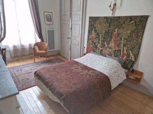 a bedroom with a bed with a tapestry on the wall at Charming apartment - Lectoure - gers in Lectoure