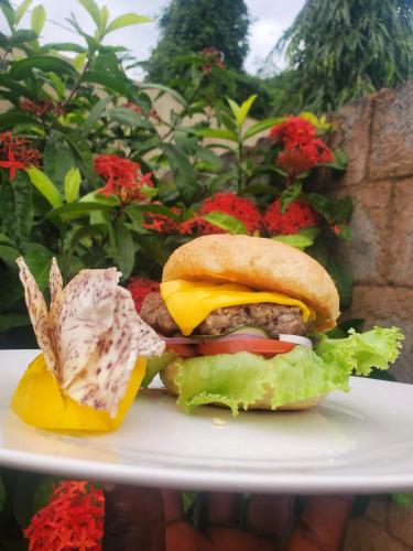 a sandwich on a plate next to flowers at Kilimanjaro Magic MJ Branch in Old Moshi
