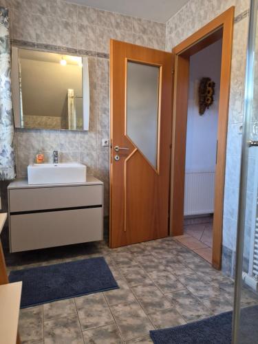 a bathroom with a sink and a mirror and a door at Ferienhof Edtmeier in Zell am Moos