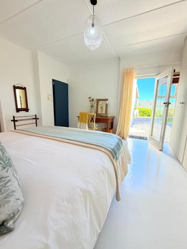 a bedroom with a large white bed with a view of the ocean at Rijke Rust, Living the Lagoon Life in Langebaan