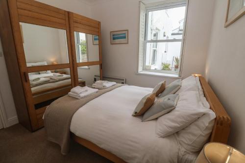 a bedroom with a bed with two pillows and a mirror at Apartment 1 Llewellan in Carbis Bay