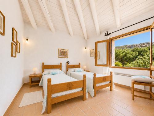 a bedroom with two beds and a large window at Sea View Three-Bedroom House 50m from the Beach in Baja Sardinia