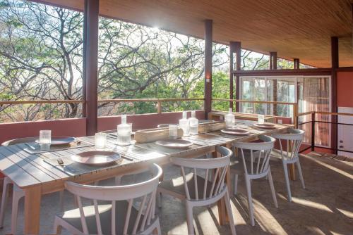a dining room with a table and chairs and windows at Tropical Design Stay near Playa Avellanas with Rooftop Terraces in Santa Cruz