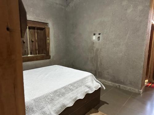 a small bedroom with a white bed in a room at Chácara do Waltinho in Contagem
