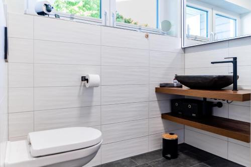 a white bathroom with a toilet and a sink at Fördezauber - Ruhiges Ferienhaus mit eingezäuntem Garten und Kamin in Bönstrup