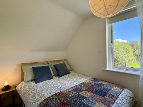 a bedroom with a bed with blue pillows and a window at Cottage 493 - Clifden in Clifden