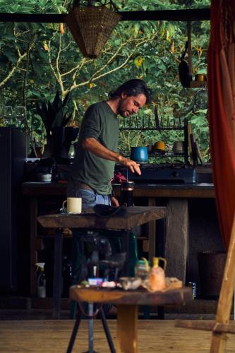 a man standing at a table preparing food at Camelia Hostel in San Carlos