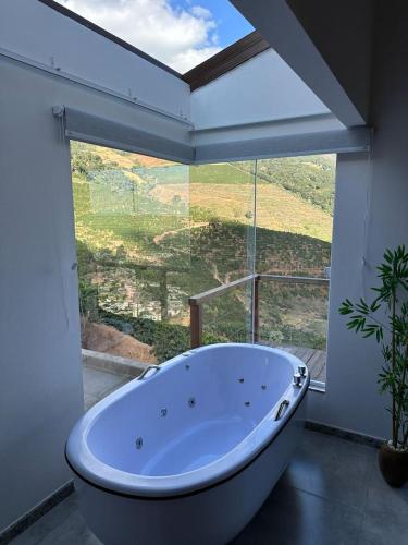 a bath tub in a room with a large window at CORAÇÃO DO ALTO CHALES Hidromassagem in Caparaó Velho