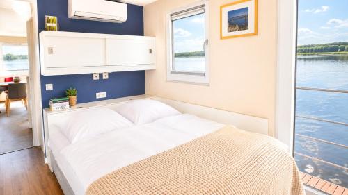 a bed in a room with a view of the water at Floatinghouse Milan - LP9 in Vetschau
