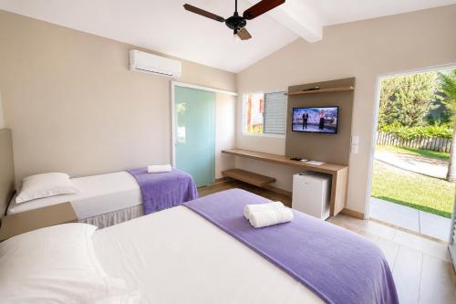 a bedroom with two beds and a tv in it at Vila da Praça Pousada in Capitólio