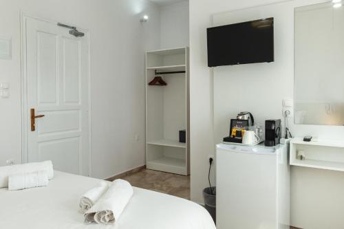 a white room with a bed and a tv on the wall at Argo Rooms-Papadakis in Kissamos