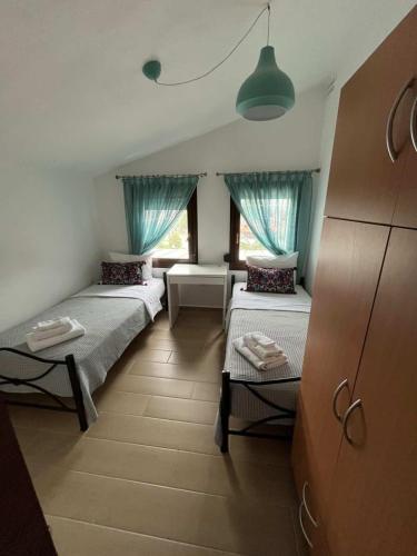 two beds in a room with blue curtains at Angie Apartment in Ierissos
