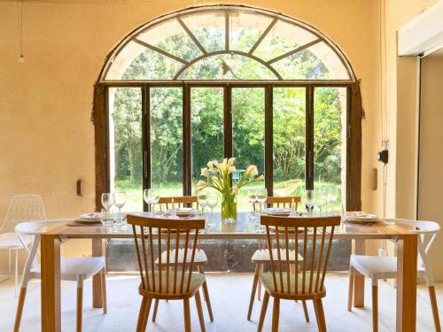 a dining room with a table and chairs and a large window at Mas provençal - Idéal familles & amis - Piscine privée - 3 suites - Avignon & Châteauneuf-du-Pape - Parking privé gratuit in Bédarrides