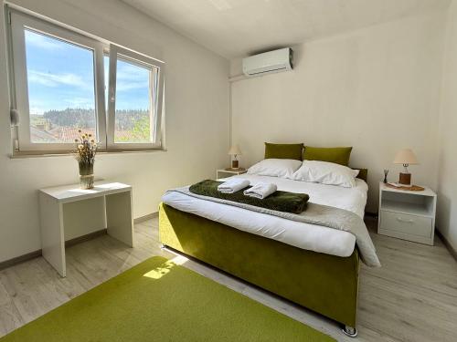 a bedroom with a large bed and two windows at Green House Cuprija in Stolac