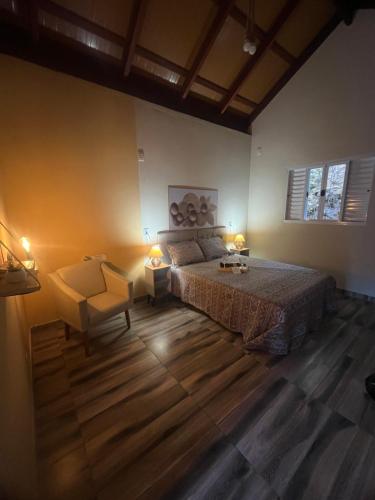 a bedroom with a bed and a chair and two lamps at Chale Azul Aconchegante com lareira no bosque e estacionamento grátis in Extrema