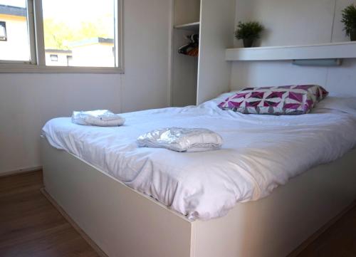 a white bed with two pillows on top of it at 't Veldhuisje 110 - naast het bos, honden toegestaan in Anloo