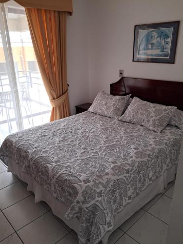 a bedroom with a bed with a gray comforter at Apart Antofagasta in Antofagasta