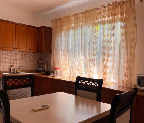 a kitchen with a table and a window with curtains at Berat Private Appartment in Haxhialiu Villa in Berat