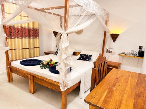 a bedroom with a canopy bed and a wooden table at Beach Wave Hotel in Arugam Bay