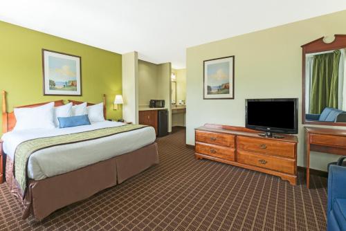 a hotel room with a bed and a flat screen tv at Baymont by Wyndham Louisville South/Shepherdsville/I 65 in Brooks