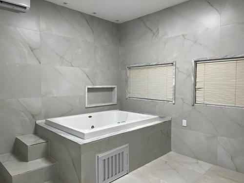 a white bathroom with a large tub and a window at Duplex mansão Manaus in Manaus