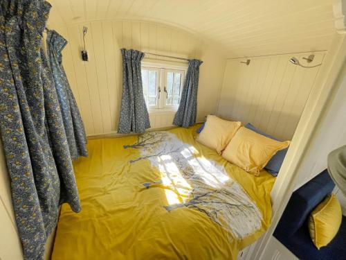 a small room with a yellow bed in the corner at The Shepherds Hut in Wallingford