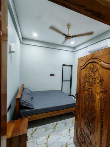 a bedroom with a bed and a wooden door at VIN Solara Farm Stay in Jaffna
