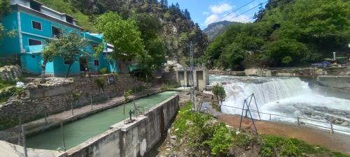 a waterfall in a river with a blue building at The Cozy Cottage in Kundālshai