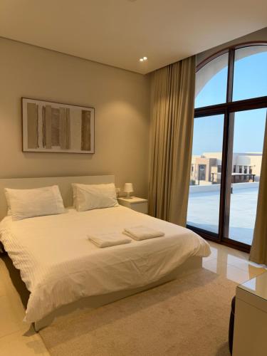 a bedroom with a large bed and a large window at Beach front 414 villa private pool in Muscat