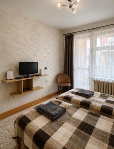 a hotel room with two beds and a tv at Krisiya's Apartment in Bansko