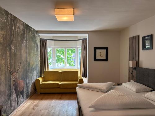 a bedroom with a bed and a couch and a window at Hotel Goldener Löwe in Kufstein