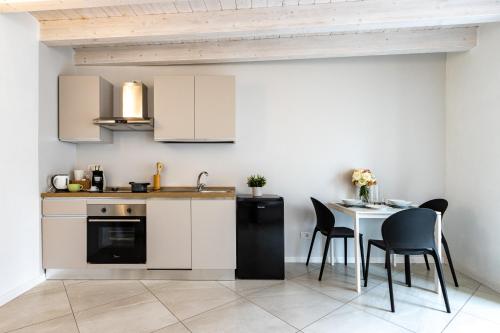 a kitchen with white cabinets and a table and chairs at Al Castello - fresco e ben isolato appartamento in Calolziocorte